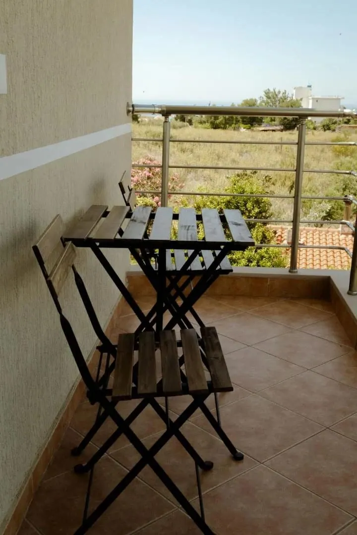 A folding table and two chairs on a private balcony above the garden
