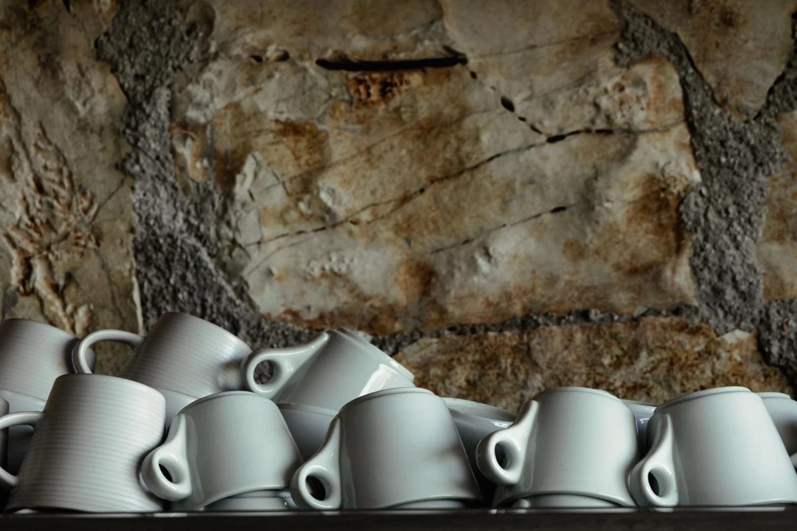 Stacked white coffee cups in a niche in the stone wall