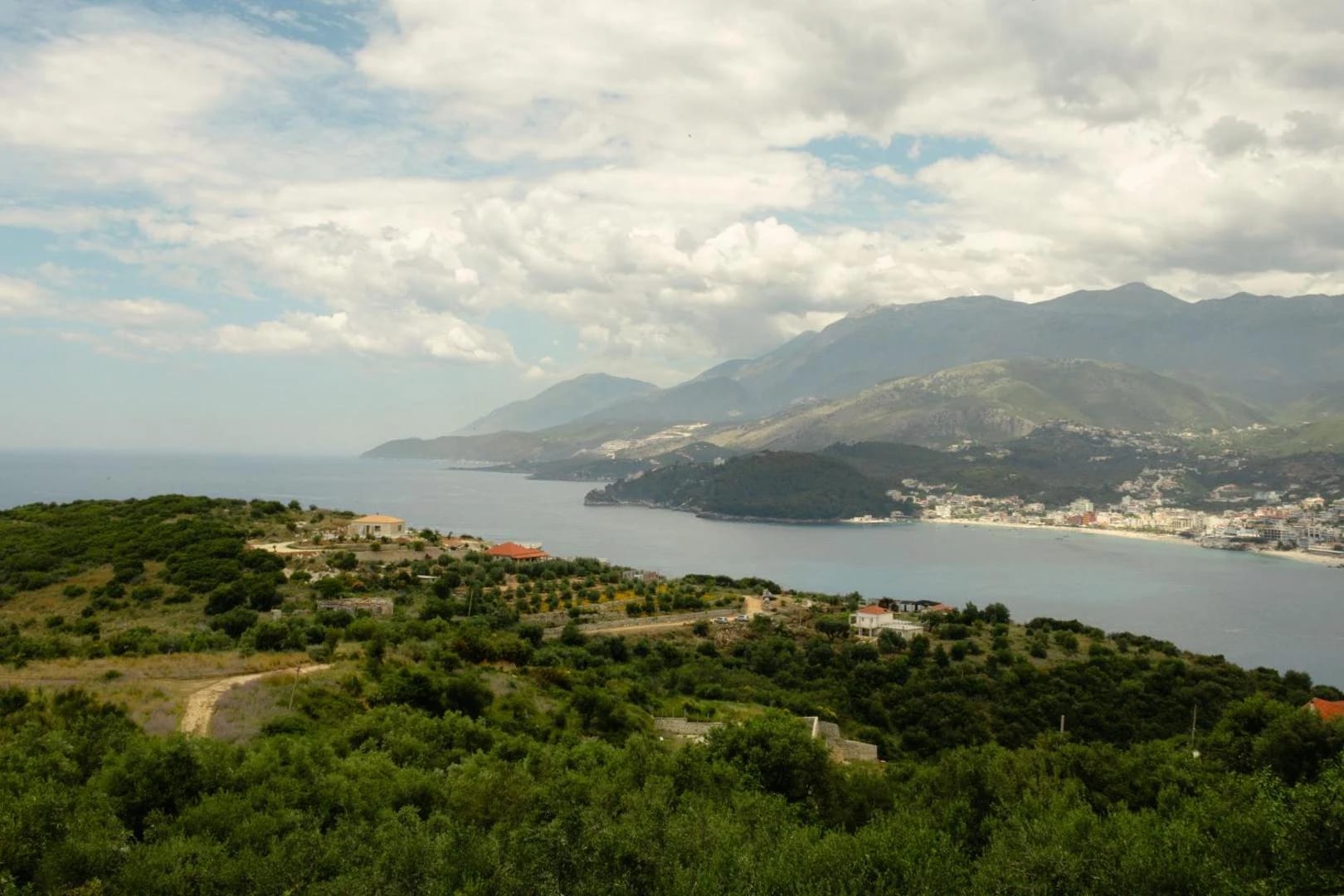A daytime panorama from the property over the wooded headland, Himarë bay and the coastal mountains behind